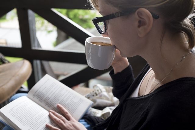 コーヒーを飲みながら読書をする女性
